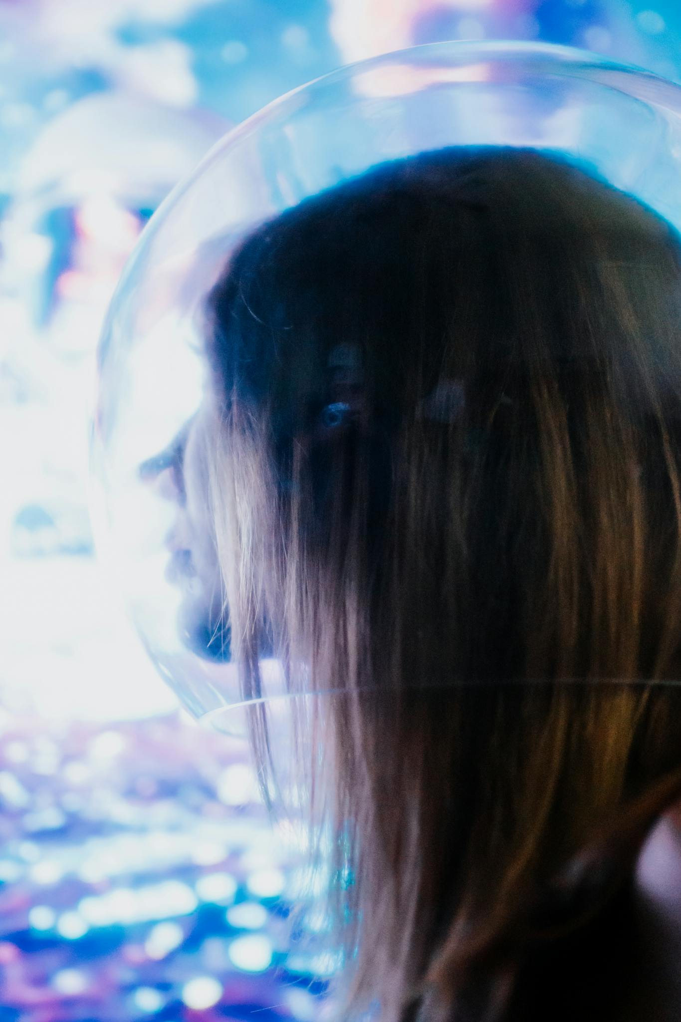 A woman wearing a transparent futuristic helmet, side view.